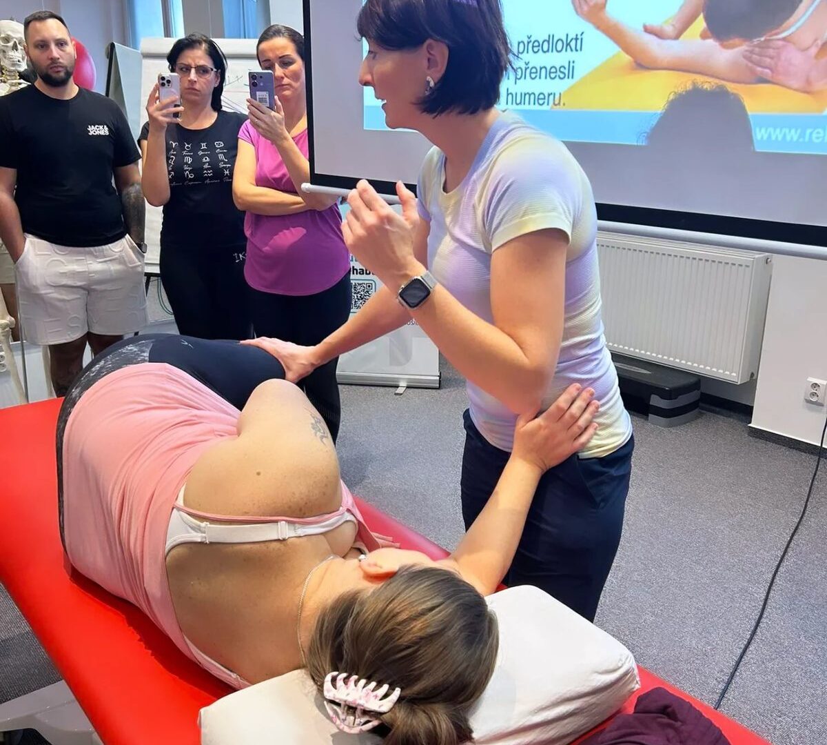 Lektorka predvádza nastavenie trupu a hornej končatiny v polohe na boku na kurze DNS – Dynamická neuromuskulárna stabilizácia v Košiciach.