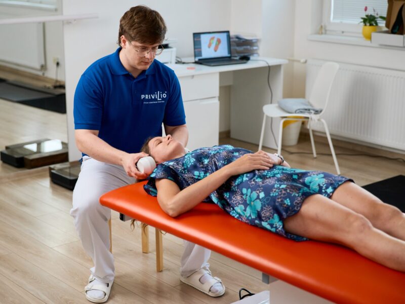 Fyzioterapeut nasádza klientke slúchadlá s vedenou meditáciou a binaurálnymi beatmi počas relaxačnej služby MindRehab v Košiciach.
