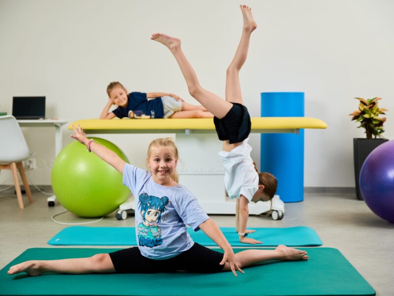 Deti predvádzajú gymnastické prvky – šnúru a stojku – počas skupinového programu MINI MOVE v Košiciach.