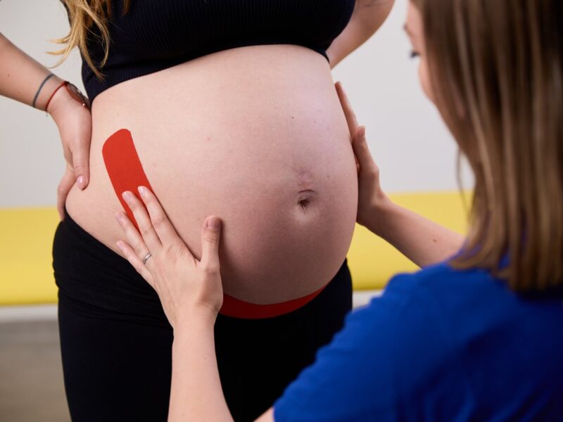 Fyzioterapeutka aplikuje kineziologický tejp na brucho tehotnej klientky v rámci ženskej fyzioterapie v Privilio Košice.