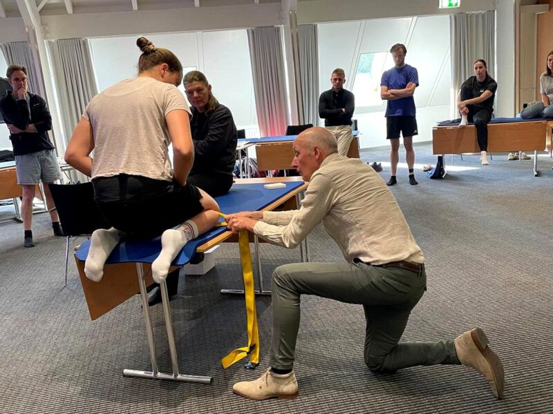 Lektor predvádza mobilizačnú techniku dolnej končatiny s použitím popruhu na kurze Mulligan koncept – Spodný kvadrant v Košiciach.