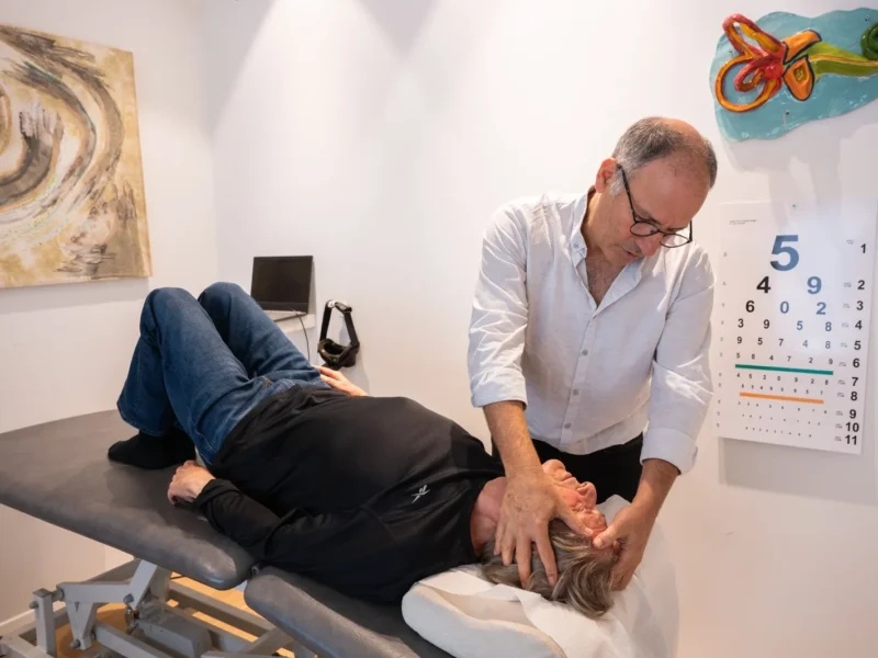 Lektor Dr. Oz Zur vykonáva polohový manéver Dix-Hallpike pri vyšetrení BPPV — benígneho paroxyzmálneho polohového vertiga.